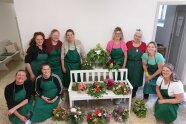 Personengruppe steht und kniet um Bank mit Blumengestecken