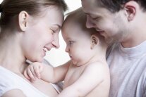 Nacktes Baby zwischen zwei Personen