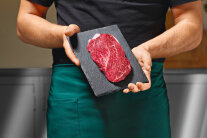 Mann hält Schieferplatte mit Rindersteak