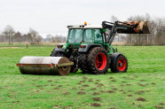 Traktor mit Walze auf Grünland